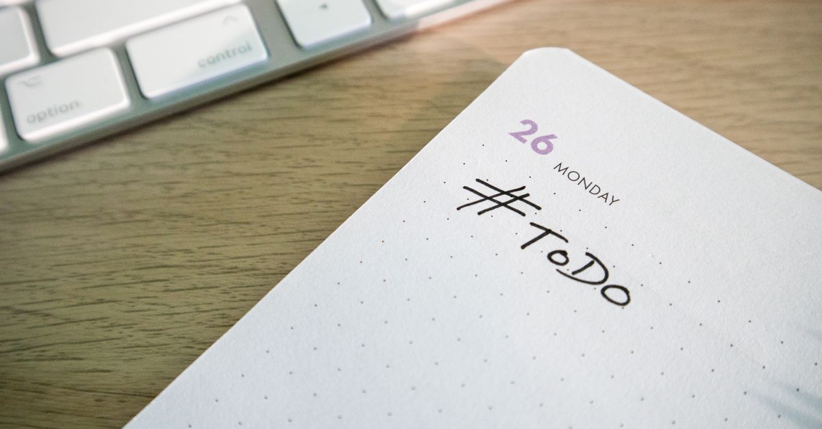 Close-up of a to-do list next to a computer keyboard on a desk.